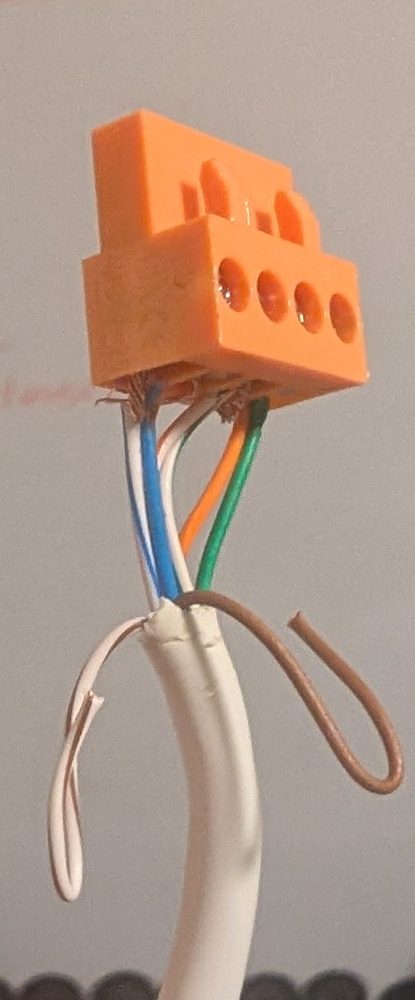 The cut end of a white CAT 5e cable, with its twisted pairs pushed into an orange four-way screw-terminal plug.